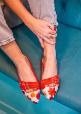 Bailarinas destalonadas celestes con bordado floral multicolor, tiras rojas con hebillas y suela de cuero.
