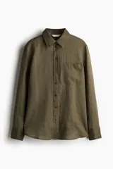 Camisa verde militar de lino liviano con cuello, botones adelante y canesú de doble capa en la espalda. Modelo con hombros apenas caídos, mangas largas con puños abotonados, bolsillo superior de parche y bajo levemente redondeado.