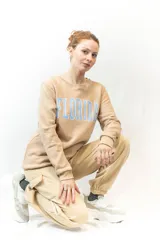 Sweater gris de corte clásico con cuello redondo y puños y cintura acanalados. Estampado frontal con la palabra "Florida" en letras celestes con borde blanco.