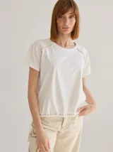 Remera color crudo de algodón con detalle de flecos en los hombros y cordón ajustable en la cintura.