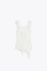 Camiseta blanca de encaje semitransparente con escote cuadrado, tirantes anchos con volantes y lazos ajustables en el frente.