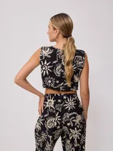 Top corto negro con estampado de flores y figuras geométricas en color crema, con breteles anchos y lazo ajustable en la cintura.