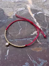 Pulsera roja regulable con cierre nudo macramé, con cuentas de 2mm en oro laminado 14k (Goldfilled) y punto de luz engarzado en oro laminado.