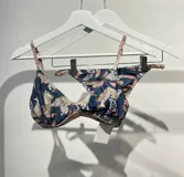 Conjunto de bikini blanco con estampado de manchas negras. El corpiño es de triángulo fijo con tirantes finos y la bombacha es tipo less regulable.
