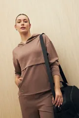 Canguro marrón con capucha, corte amplio y detalle de recorte frontal.