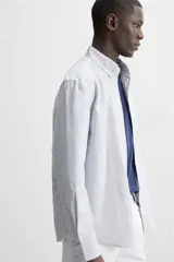 Camisa azul marino de corte regular fit, confeccionada en tejido de algodón Oxford. Tiene cuello abotonado, manga larga con puños abotonados, bolsillo de parche en el pecho y cierre frontal con botones.