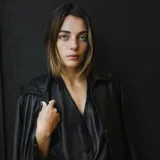 Chaleco negro sin espalda confeccionado en cuero ovino, con cuello halter y cierre frontal con botones.