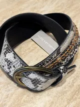 Cinturón de cuero con estampado de piel de serpiente en tonos blanco, gris y negro. Presenta una hebilla ovalada de metal color bronce y detalles de costuras en hilo color cobre.