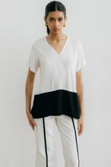Remera blanca con corte horizontal y parte inferior negra. Cuello en V y mangas cortas.