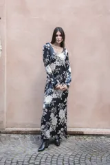 Vestido largo de seda color negro con estampado de flores blancas, palmeras y tigres. Tiene escote en V, mangas largas y lazo en la espalda.
