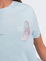 Remera celeste con estampado de un teléfono celular antiguo y la frase "Call me".