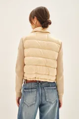Campera color beige con mangas tejidas, cuello alto y cierre frontal.
