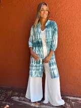 Camisa larga de manga tres cuartos, color verde azulado y blanco, con estampado tie-dye. Tiene cuello camisero, botones frontales y bolsillos en el pecho.