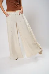 Pantalón palazzo color beige con bordados calados en forma de paisley en los laterales.