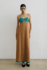 Vestido largo color marrón de gamuza con breteles finos, escote redondo, bordado floral turquesa en el escote y galón turquesa en el ruedo.