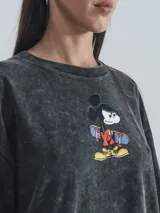 Remera negra con efecto nevado, de corte oversize y manga corta. Estampado frontal con Mickey Mouse en patineta y llamas.