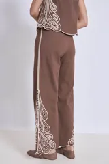 Pantalón blanco de corte ancho con bordados calados en forma de hojas en el ruedo.