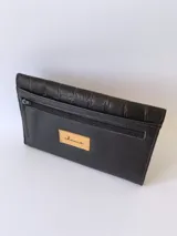Billetera de cuero negro con textura tipo cocodrilo y cierre con broche. Tiene monedero externo y detalle de tres hojas grabadas en el frente.