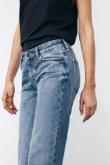 Pantalón de jean celeste de tiro bajo, corte flare, cropped y cinco bolsillos.