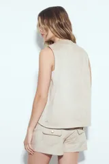 Chaleco corto negro con apliques metálicos plateados en forma de diseño orgánico en el frente.