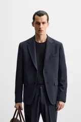 Blazer slim fit azul marino confeccionada en tejido con 17% de lana. Cuello con solapas de muesca, manga larga acabada en puño con detalle de botones, bolsillo de vivo en pecho y de solapa en cadera, detalle bolsillo interior, bajo con aberturas en espalda y cierre frontal con botones.