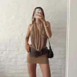 Vestido corto color beige, con escote halter y espalda descubierta. Ajustado al cuerpo y confeccionado en microtul.