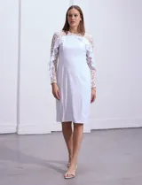 Vestido blanco de seda fría, corte midi ajustado al cuerpo, con mangas largas de encaje con brillos y aplique fruncido en el hombro.