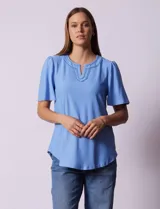 Blusa celeste de tejido piqué, con cuello a la base y escote en V. Tiene mangas cortas amplias.
