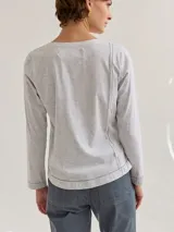Remera gris claro de algodón con escote en V y bordados dorados y azul marino en los hombros.