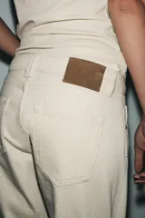 Jeans de tiro medio color beige, corte cigarette, con cinco bolsillos y cierre frontal de cremallera y botón.