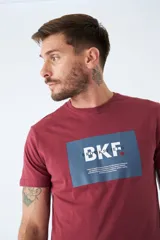 Remera de algodón color bordó con estampado rectangular azul con letras blancas en el frente.