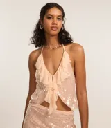 Blusa color rosa pálido con lentejuelas y volados, de escote halter y espalda descubierta.
