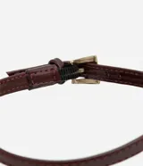 Zapato de tacón color marrón con punta fina, tira fina con hebilla lateral para cierre y tacón fino.