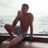 Short de baño celeste con estampado de motivos marinos en tonos azules y marrones. Tiene pretina fija con hebillas metálicas laterales, botón a presión y cierre frontal. Incluye tres bolsillos, interior de mesh hipoalergénico y accesorios waterproof.