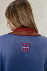 Buzo azul de algodón con cuello polo rojo con botones y puños acanalados.