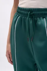 Pantalón deportivo ancho de color verde oscuro, con vivo blanco vertical en el centro de cada pierna. Presenta cordón de ajuste en la cintura y corte holgado.