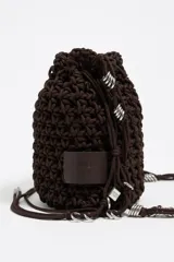 Bolso marrón tipo bucket, tejido con cordones gruesos, con asa corta y cierre ajustable con cordón. Incluye etiqueta logotipada BIMBA Y LOLA y charms metálicos plateados.