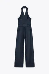 Mono largo de lino color azul marino, con cuello halter, espalda descubierta, bolsillos delanteros y cinturón del mismo tejido.