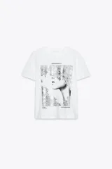 Camiseta blanca de corte recto y manga corta, con estampado frontal de una fotografía en blanco y negro y texto "Amsterdam 74".