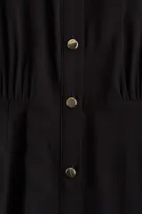 Vestido camisero midi negro con cuello camisero, botonadura frontal, mangas raglán cortas, elástico en la parte posterior de la cintura, frunces adelante y atrás, y cinturón extraíble para atar.