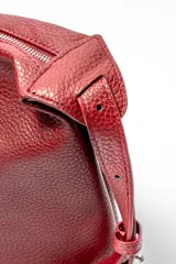 Bolso tipo hobo de cuero sintético color rojo oscuro con textura granulada.