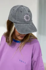 Gorra marrón de algodón con visera curva y bordado frontal con la palabra "HAHA" repetida en círculo.