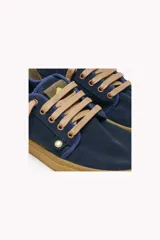 Zapatillas urbanas Satorisan modelo Heisei Suede 1.0, color azul marino, con capellada de gamuza. Presentan suela de goma color caramelo y detalles en verde lima en los cordones. El talón tiene un parche de refuerzo en color verde oliva.