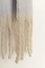 Bufanda manta de tejido suave, color blanco hueso, con flecos definidos en los bordes.
