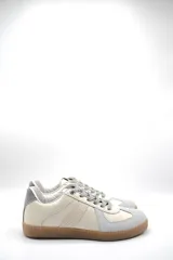 Zapatillas urbanas de cuero color crema con detalles en gris y suela de goma marrón.