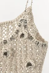 Top de crochet color beige, con tirantes finos y escote redondo. Presenta apliques de flores en relieve y abalorios plateados.