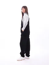 Mono enterizo negro de corte holgado con tirantes regulables y bolsillos laterales. Presenta un bolsillo tipo parche en el frente.