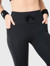 Calza deportiva negra con cintura alta ajustable con cordón, bolsillos laterales y logo estampado en la pierna.