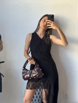 Vestido corto de encaje negro con escote en V, sin mangas y corte irregular.
