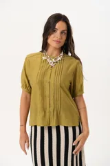 Blusa color verde oliva con cuello mao, mangas cortas abullonadas y cierre frontal con botones.